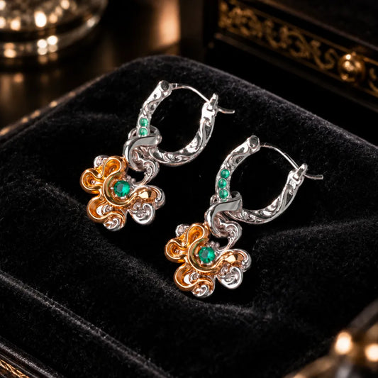 Pair of clover serpent earrings with green stones in a jewelry box