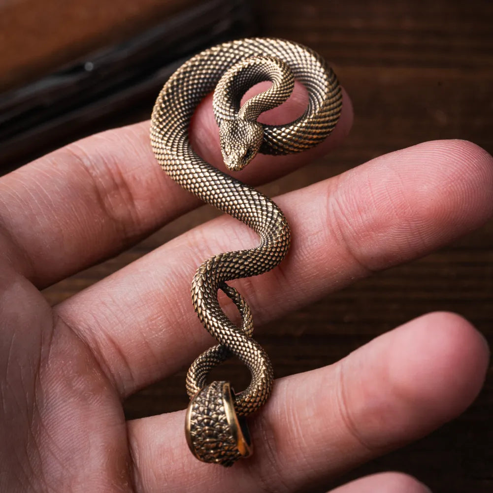 Coiled serpent keychain held between fingers, close-up; appearance reference for made-to-order editions