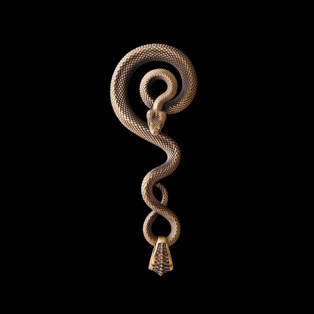 Coiled serpent keychain on its own in antiqued brass with black zircon eyes and hand-carved scales; the same design is also made to order in other materials.