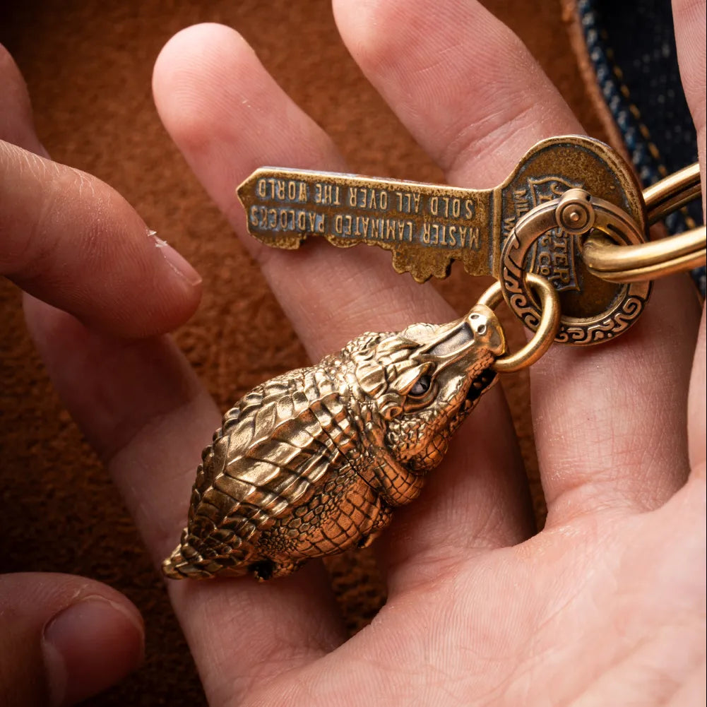 Crocodile pendant attached to a key ring and held in a hand.
