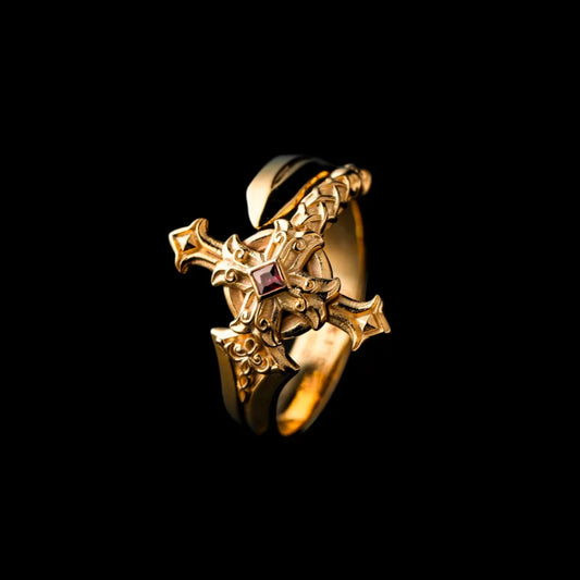 Gold-tone Judicator Blade ring with a red center stone on a black background.