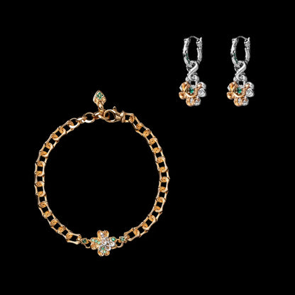 Gold-tone snake chain bracelet with a green clover centerpiece beside two matching drop earrings on a black background