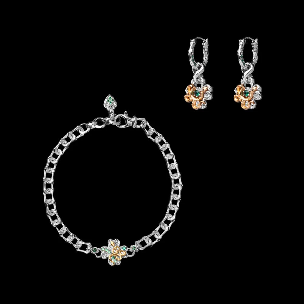Silver-tone snake chain bracelet with a green clover centerpiece beside two matching drop earrings on a black background