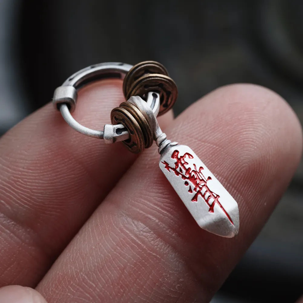 Masterblade talisman earring held in hand for a detailed view