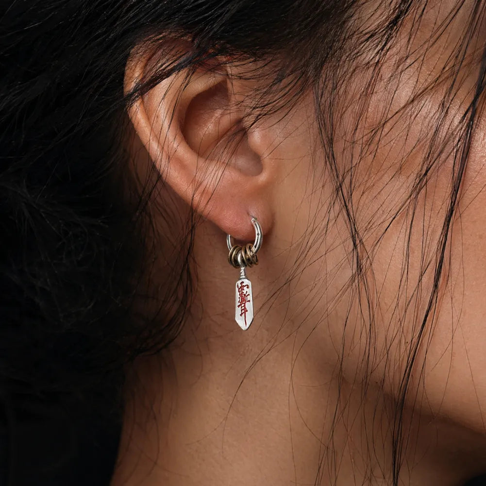 Woman wearing a Masterblade talisman earring in a close-up view