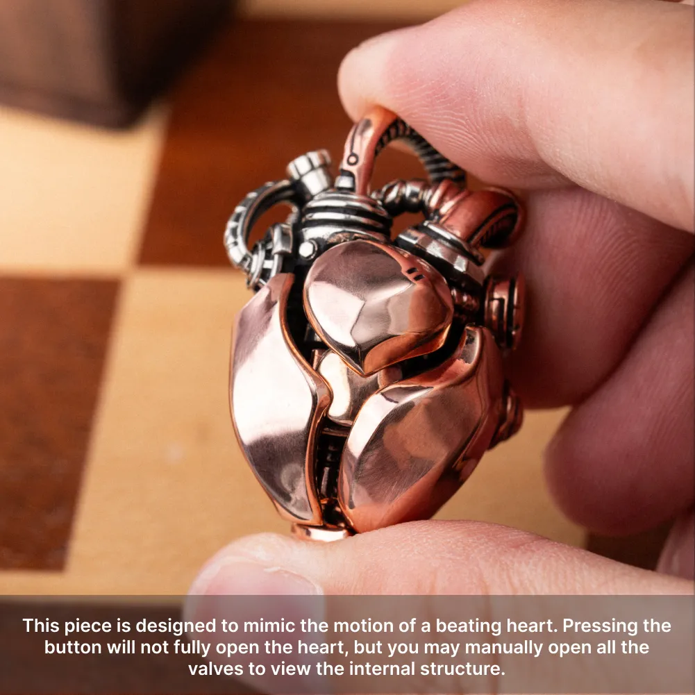 Hand holding the Copper & White Bronze Mechanical Heart Pendant to show its polished metal details
