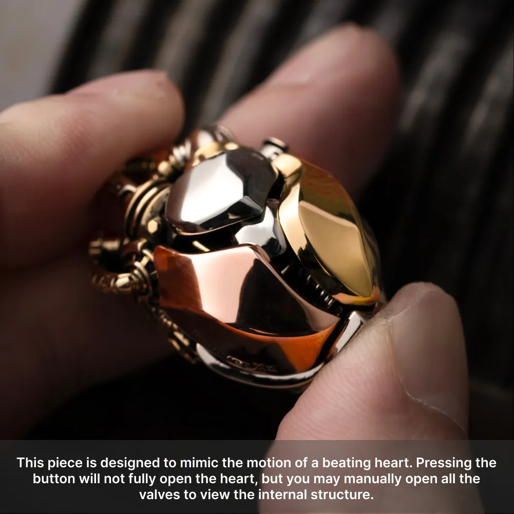 Hand holding the White Bronze & Brass & Copper Mechanical Heart Pendant to show its polished metal details