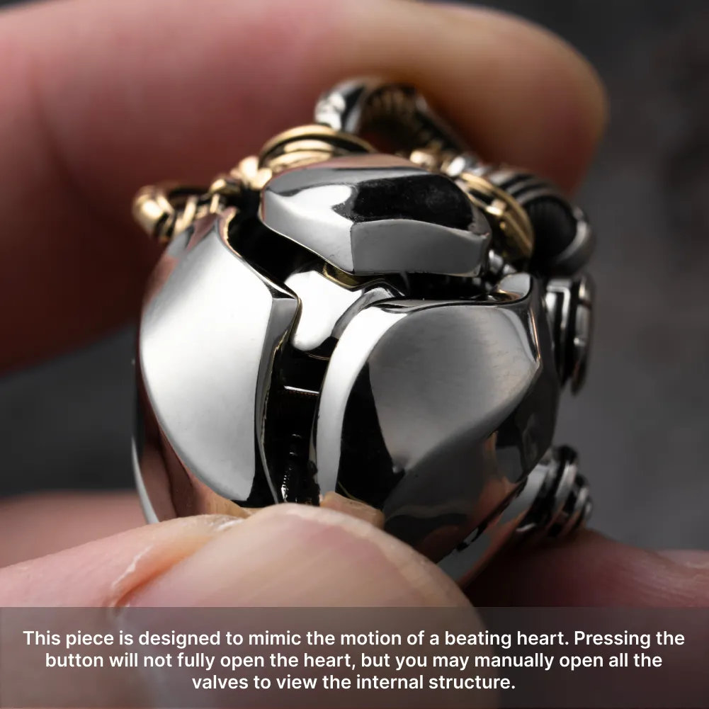 Hand holding the White Bronze & Brass Mechanical Heart Pendant to show its polished metal details