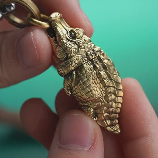 Crocodile box opener pendant shown opening a package, with a ball chain and key-ring configuration.
