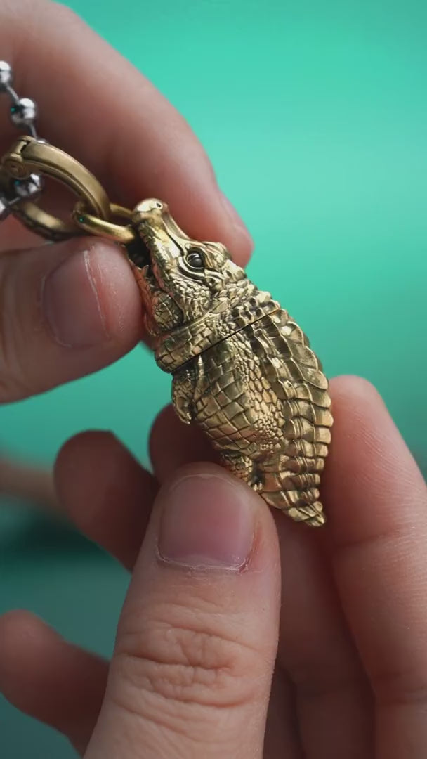 Crocodile box opener pendant shown opening a package, with a ball chain and key-ring configuration.