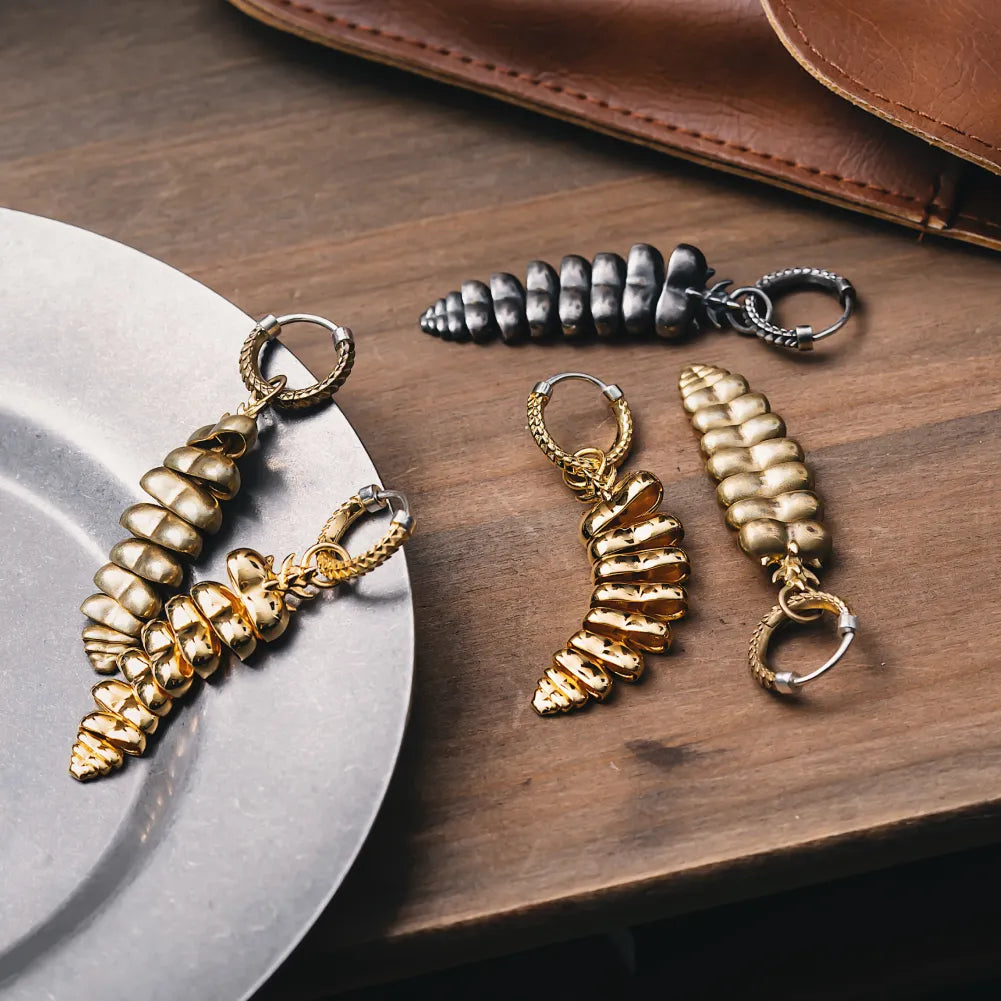 Pair of Rattlesnake Tail earrings displayed on a reflective surface