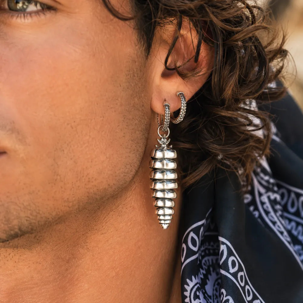 Rattlesnake Tail Earrings in White Bronze with Oxidized Sterling Silver Pins, worn by a man in a close-up ear view.