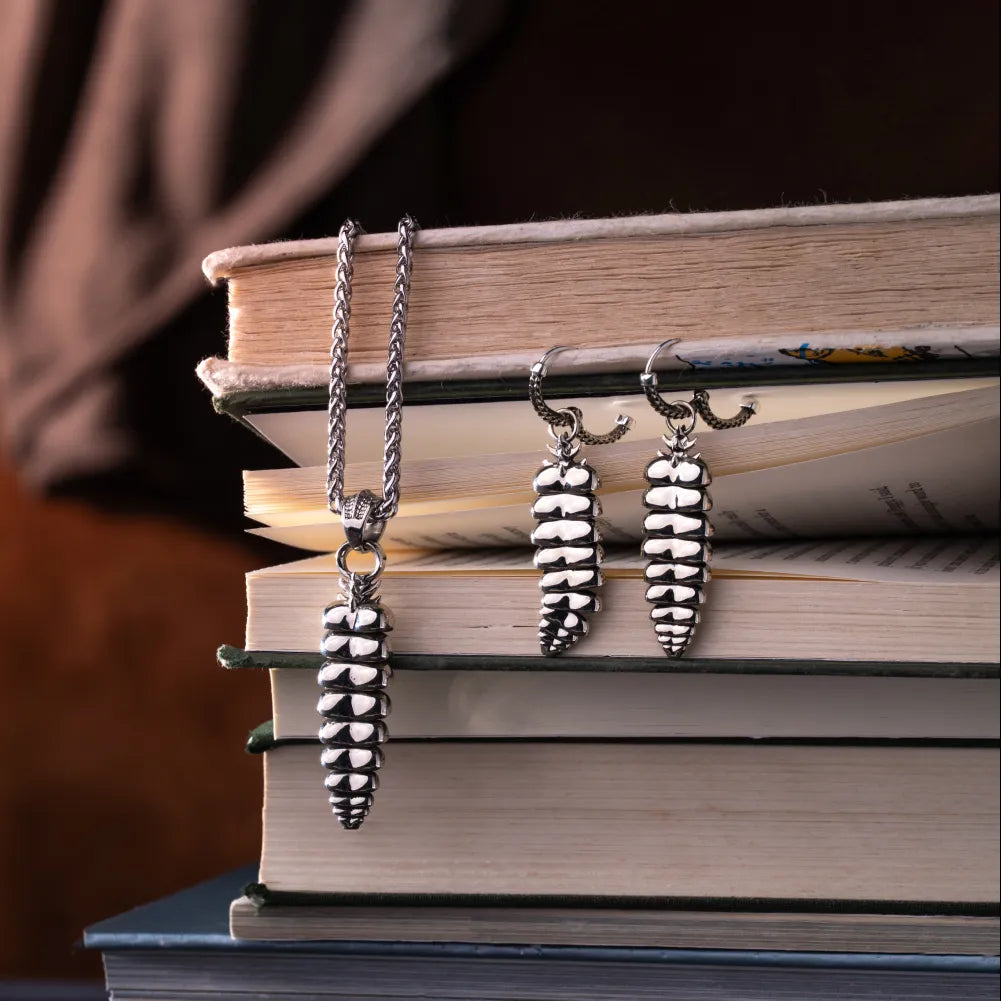 Rattlesnake Tail Earrings in White Bronze with Oxidized Sterling Silver Pins, pair displayed with chain styling over stacked books.