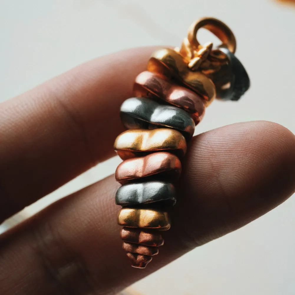 Tricolor rattlesnake tail pendant held in hand showing articulated segments