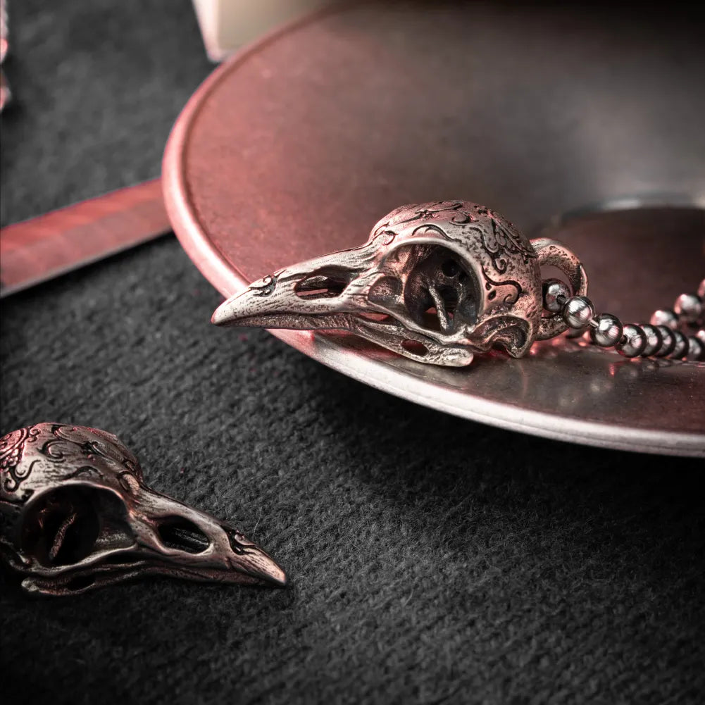 White Bronze Raven Skull Pendant on a dark leather surface