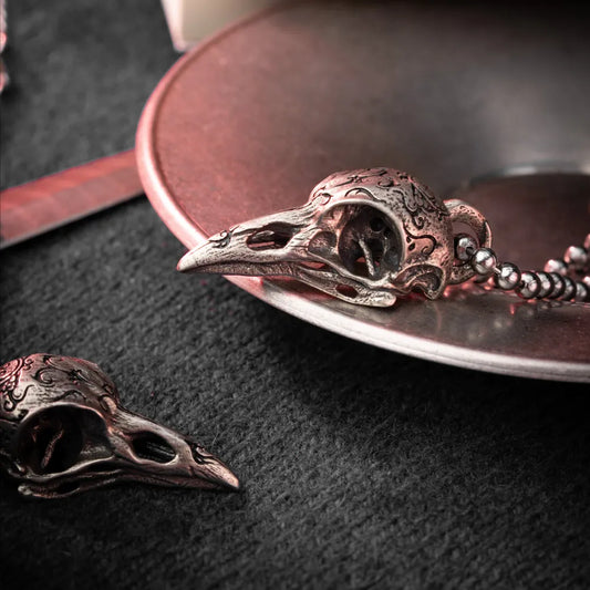 White Bronze Raven Skull Pendant on a dark leather surface