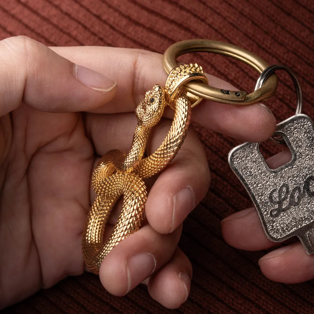 Snake Keychain in 24K Gold Plated Brass, held close up with the snake head and loop construction visible.