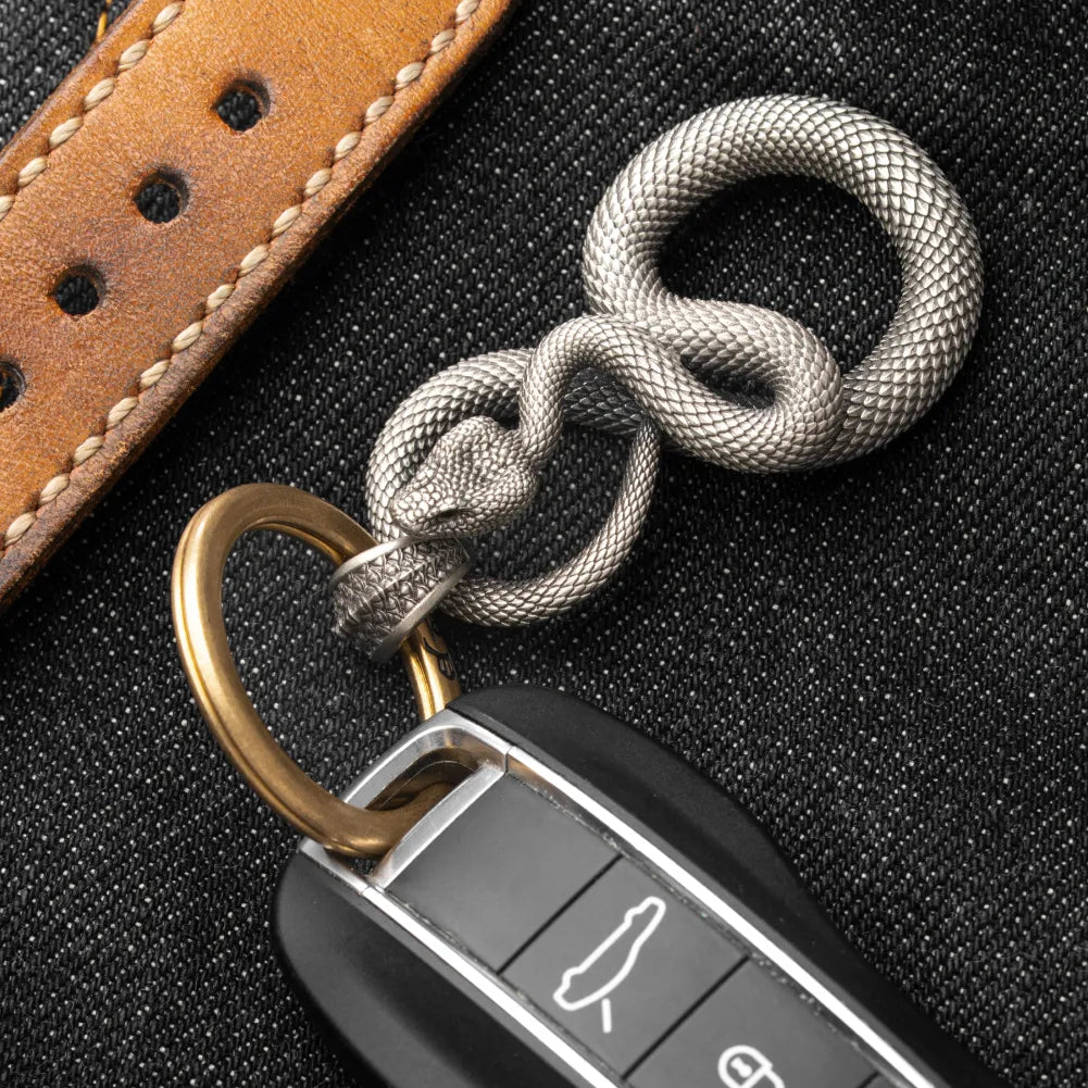 Snake Keychain in White Bronze, shown with keys in a leather-surface flat lay.