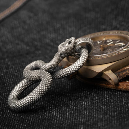 Snake Keychain in White Bronze, shown beside a wristwatch in a product close-up.